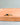 A gold ring with a round-cut dark blue gemstone, resting on a terracotta-colored ceramic tray against a neutral gray background.