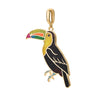 A gold-toned enamel toucan pendant charm, featuring a black body, yellow chest, and a vibrant multicolored beak with green, yellow, pink, and red, set against a plain white background.