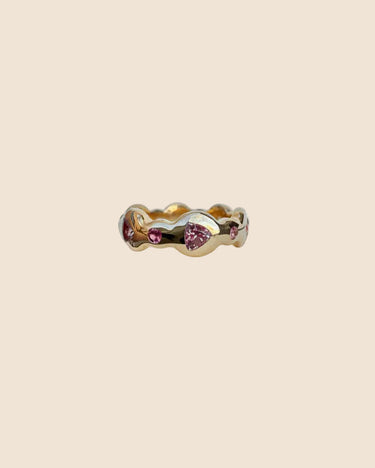 Gold ring with pink gemstones on a beige background
