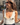 Leandra Medine wearing a cream knit sleeveless top with prominent gold buttons, styled with a gold choker and sunglasses, standing on a city street.