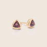 Pair of gold stud earrings with embedded sapphires on a cream background